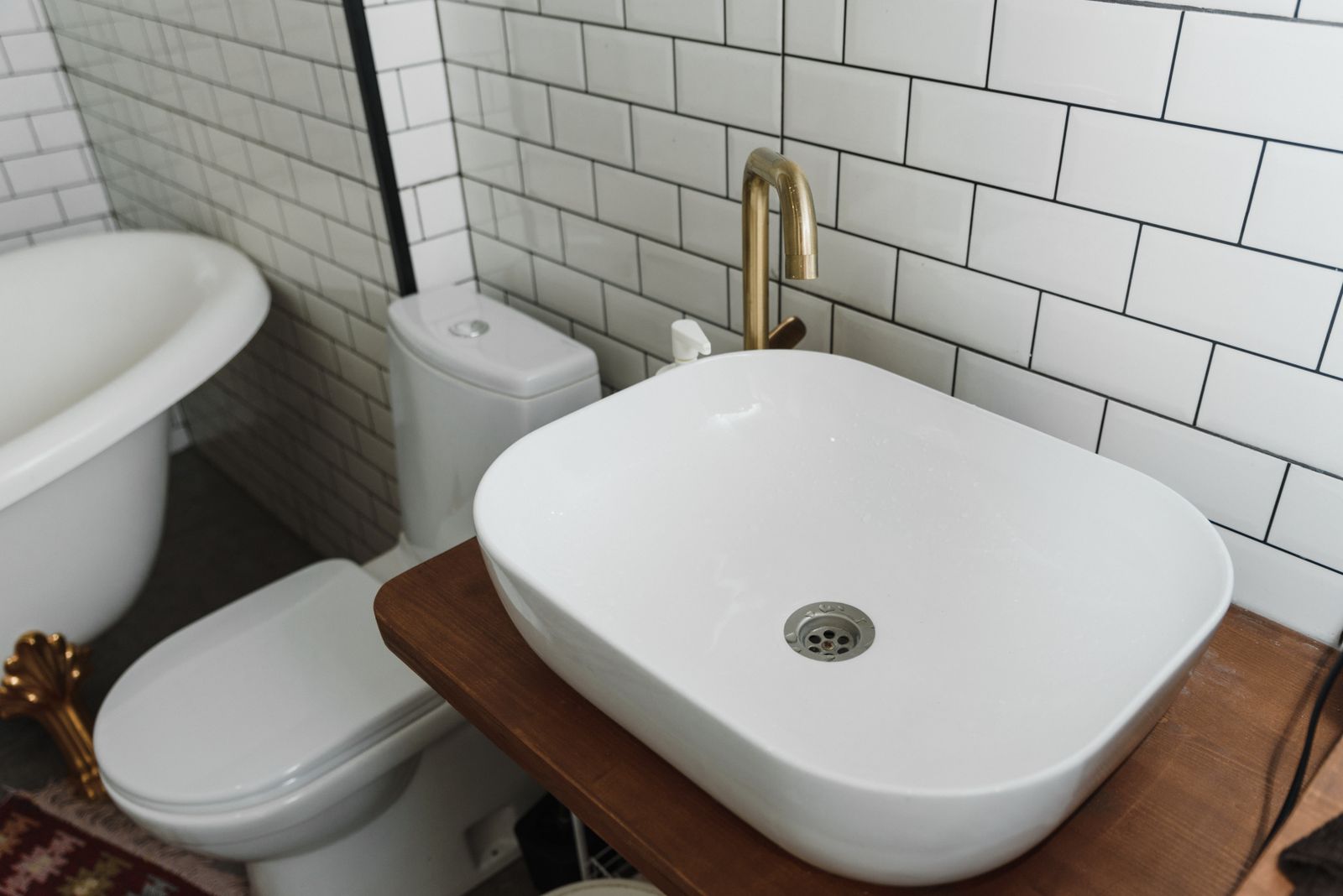 Salle de bains rénovée : vasque blanche sur plan en bois et carrelage métro